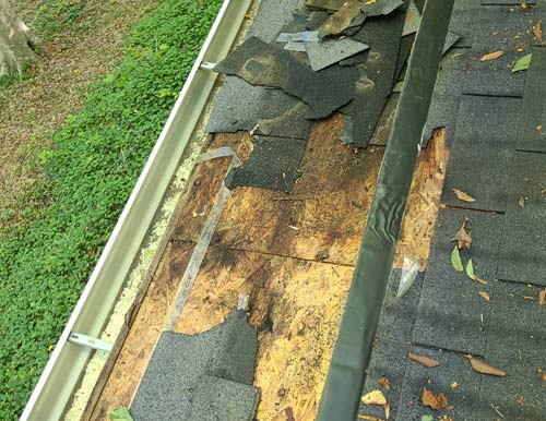 Removing old roof shingles damaged with water damage underneath